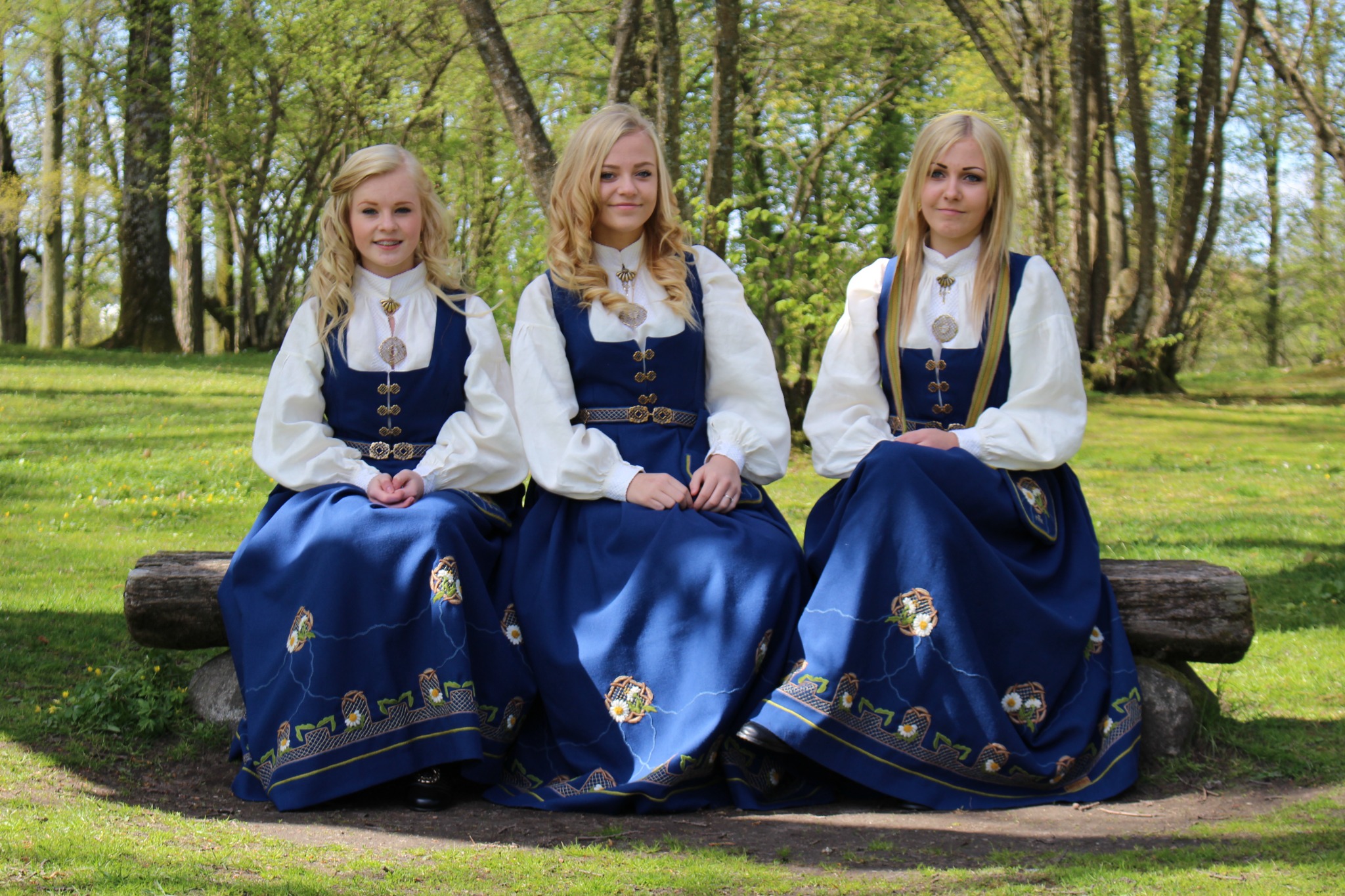 Tre kvinner i Borgfestdrakt med prestekrager – Sarpsborgs kommuneblomst